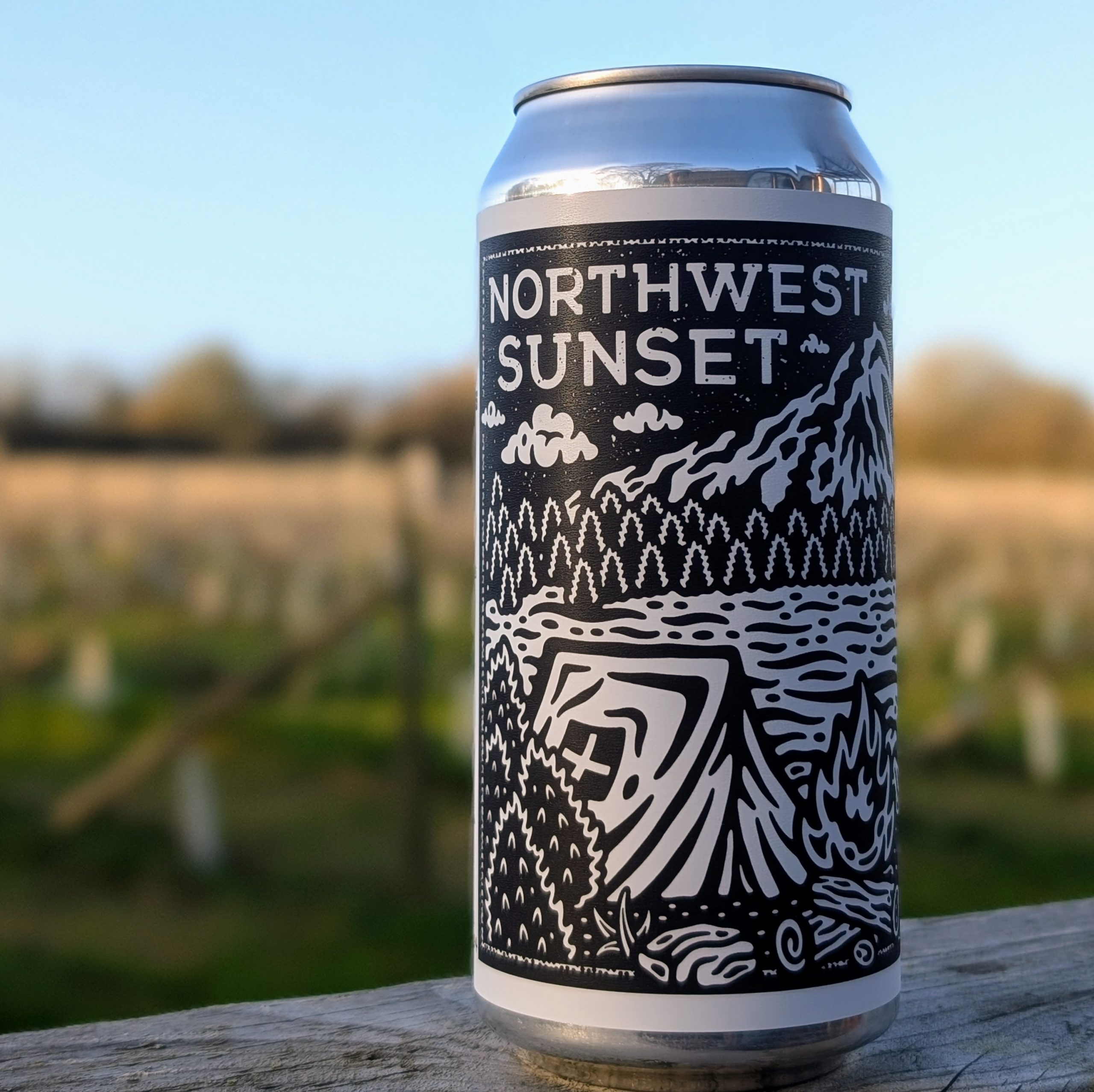 A close up of Northwest Sunset beer can with a vineyard backdrop