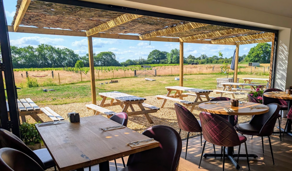 Cafe tables and chairs with open bifold doors looking out over the vineyard